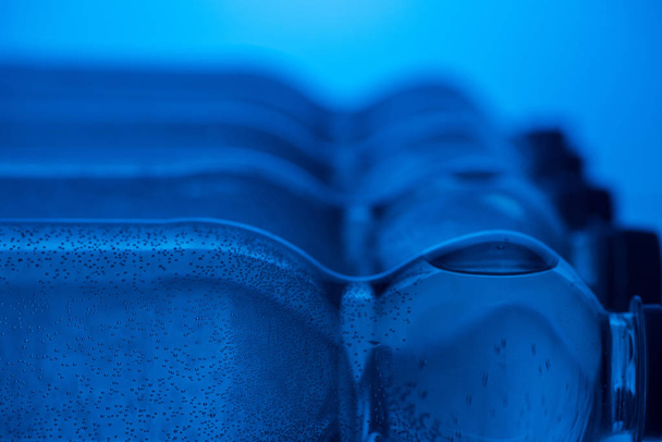 Close up van plastic flessen van water met bubbels en kopieer ruimte op blauwe achtergrond - Foto, afbeelding