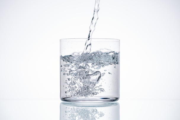 water pouring in drinking glass on white background with backlit - Foto, Imagem