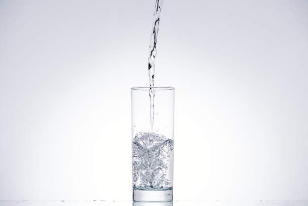l'eau versant dans le verre sur fond blanc avec rétro-éclairage et espace de copie
 - Photo, image