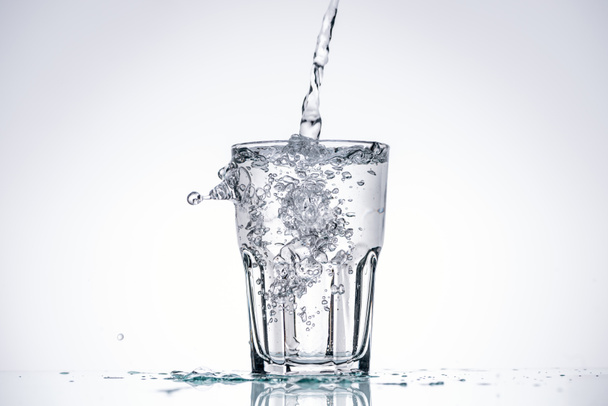 water pouring in glass on white background with backlit, splashes and copy space - Photo, Image