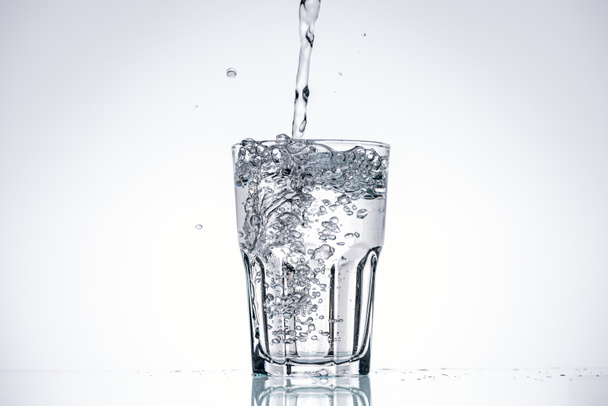 water pouring in drinking glass on white background with backlit and copy space - Photo, Image