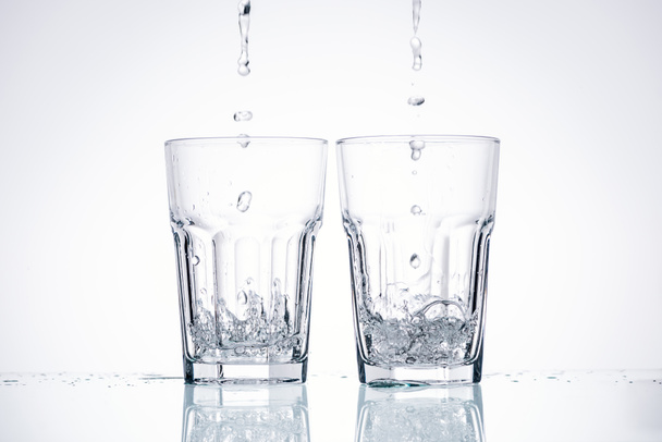 water pouring in glasses on white background with backlit - Foto, imagen