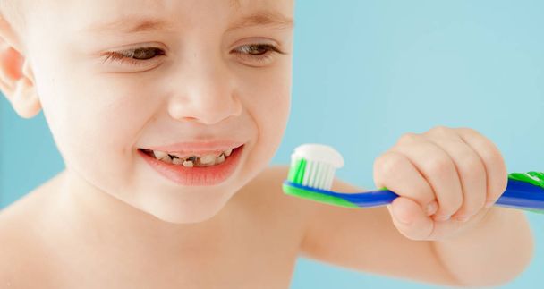 Portrait of little boy with toothbrush on blue background - Photo, Image