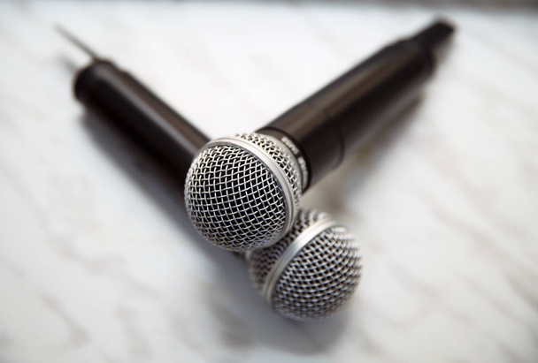 Dwa srebrne mikrofony odizolowane na białym tle. Dwa bezprzewodowe mikrofony na stole konferencyjnym. - Zdjęcie, obraz
