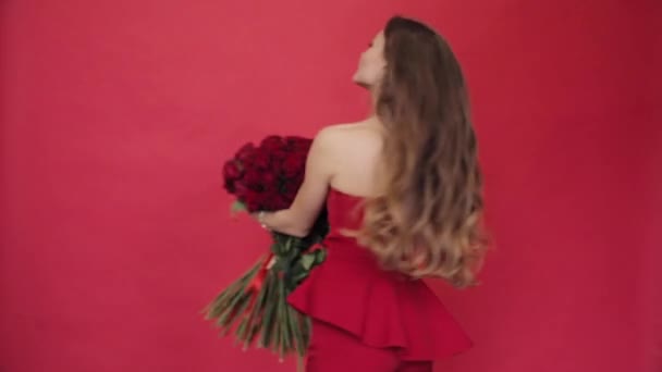 Gorgeous woman in red dress spinning with bouquet of roses - Filmati, video