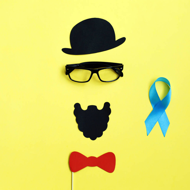 изображение человека на бумаге. Шляпа в солнечных очках и голубая лента. Концепция рака предстательной железы
 - Фото, изображение