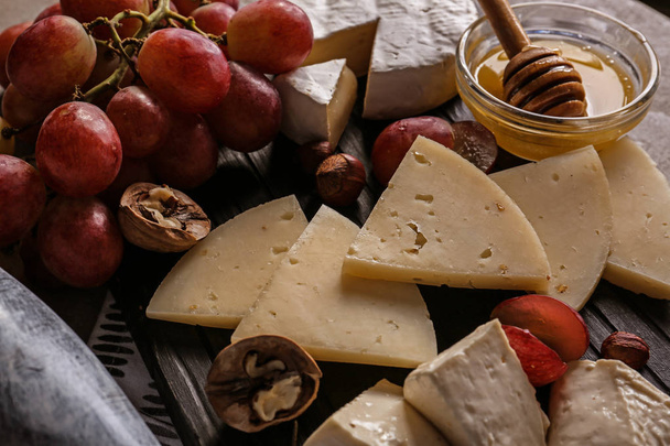 Ποικιλία από νόστιμα τυριά με μέλι και σταφύλια επί του σκάφους - Φωτογραφία, εικόνα