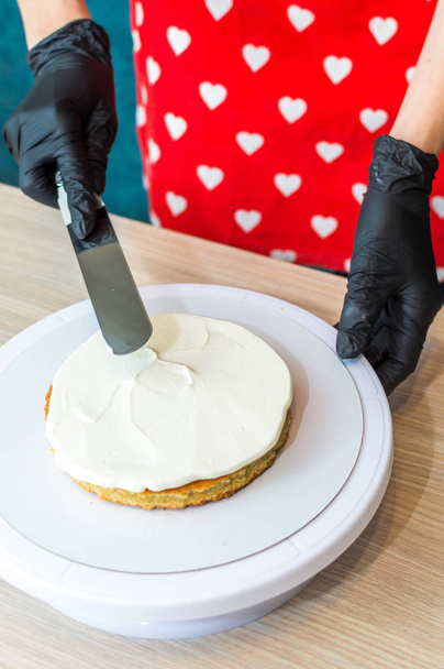 pastry chef puts cream on a sponge cake. Cake making process - Foto, Imagen