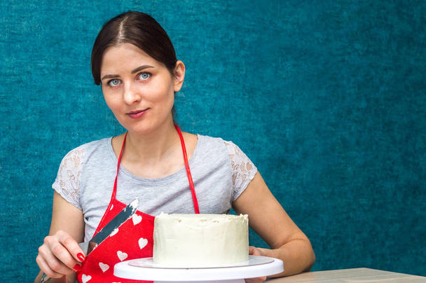 Housewife Shapes Sponge Cake. Copy space. Blue background - Foto, Bild