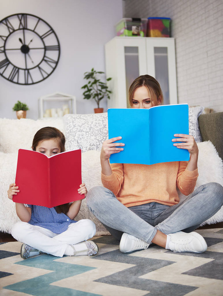Mom and child reading a book in living room  - Фото, изображение