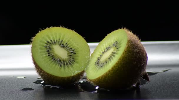 Kiwi gesneden in de helft draaiend op zwarte achtergrond - Video