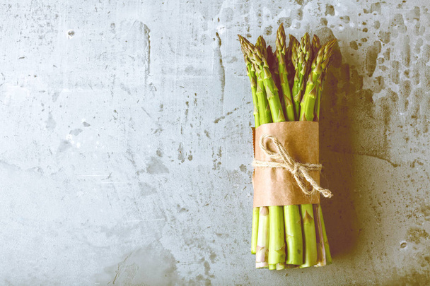 top view of fresh raw green tied asparagus on grey background   - Foto, afbeelding