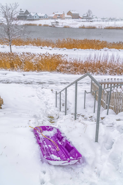 Sanki na śniegu z jeziora i domów w tle - Zdjęcie, obraz