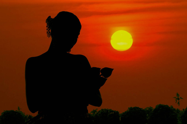 die schwarze Silhouette Frau steht und umarmt eine Lotusblume bei su - Foto, Bild