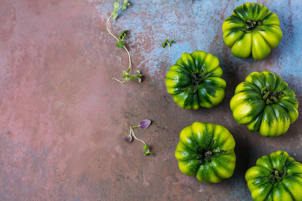 top view of fresh green organic tomatoes with leaves on grey surface - Foto, Bild