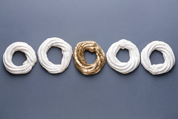 Gouden meringue van witte ones op grijze achtergrond. Concept van uniciteit - Foto, afbeelding