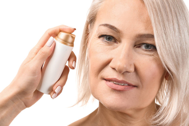 Female hand applying serum onto mature woman's face against white background - Photo, Image