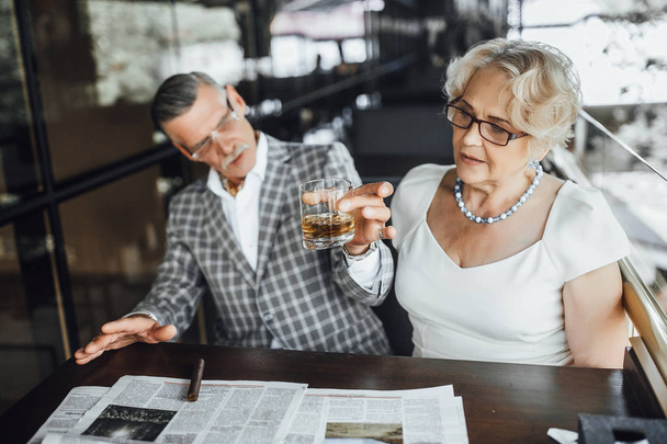 senior couple drinking wine at summer terrace and reading newspaper - Foto, imagen