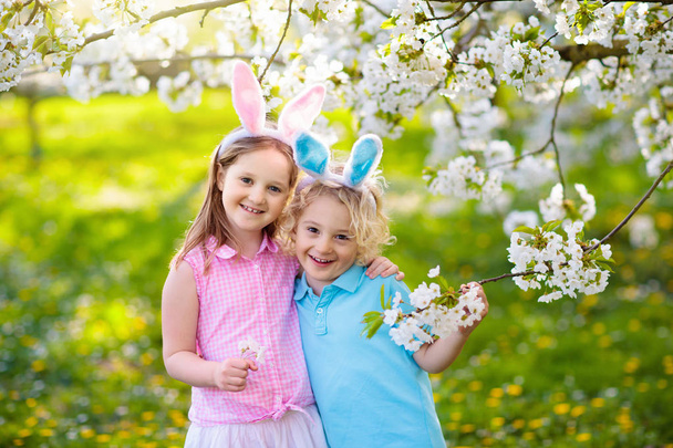 Húsvéti tojás vadászat. Gyerekek nyuszi füle és kosár. - Fotó, kép