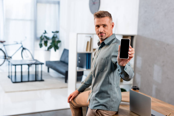 podnikatel, držení smartphone s prázdnou obrazovkou v moderní kanceláři - Fotografie, Obrázek