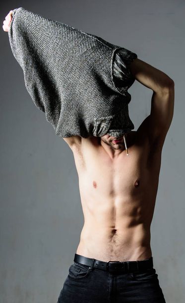 Guy sexy muscular torso take off clothes grey background. Seductive macho feeling sexy. Bohemian sexy body. Object of desire concept. Caught in state of undress. Man handsome sexy hipster undressing - Фото, изображение