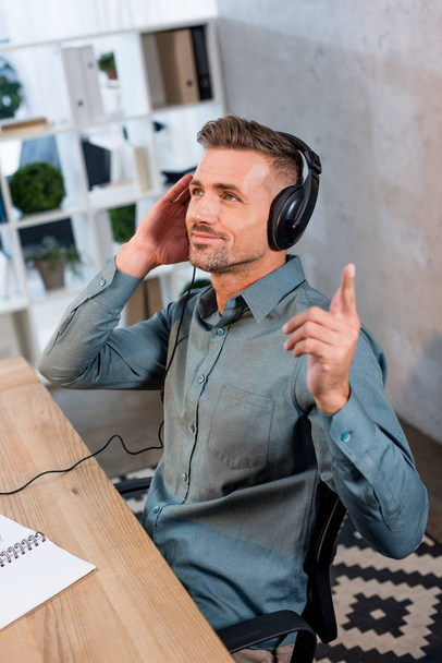 happy businessman listening music in headphones in modern office - Фото, зображення