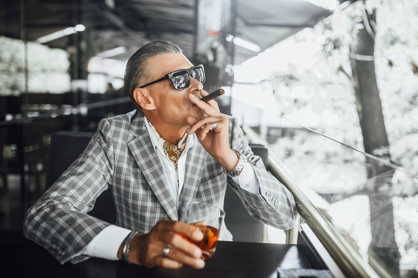 businessman in suit with suspicious face drinking beverage and smoking - Φωτογραφία, εικόνα