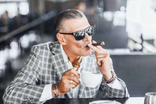 Businessman drinking beverage and smoking cigarette on summer terrace - Φωτογραφία, εικόνα