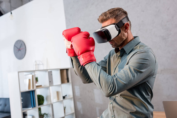 homme d'affaires sérieux portant casque de réalité virtuelle et gants de boxe au bureau
 - Photo, image