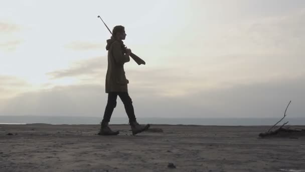 Jonge Stalker vent met geweer en geschilderd gezicht lopen in bewolkt post apocatyptic woestenij. Stalker-Survival concept - Video