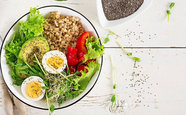 Friss salátával. Reggeli tál zabkását, paprika, avokádó, saláta, microgreens és főtt tojás. Egészséges étel. Vegetáriánus buddha tálba. Szemközti nézet - Fotó, kép