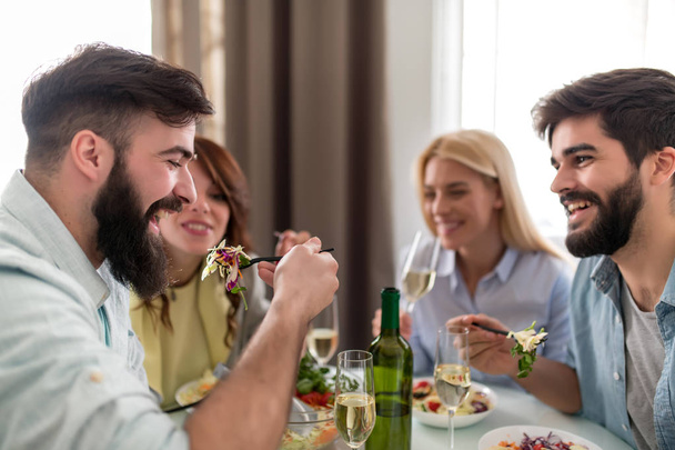 Groep vrienden vieren met alcohol en voedsel aan eettafel. - Foto, afbeelding