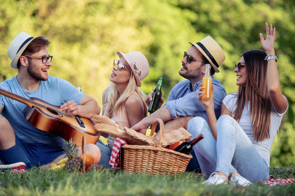 Summer, vacation, music and recreation time concept.Cheerful  friends having picnic,enjoying sunny warm day. - Фото, зображення