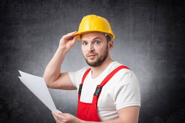 Confused construction worker holding papers - 写真・画像