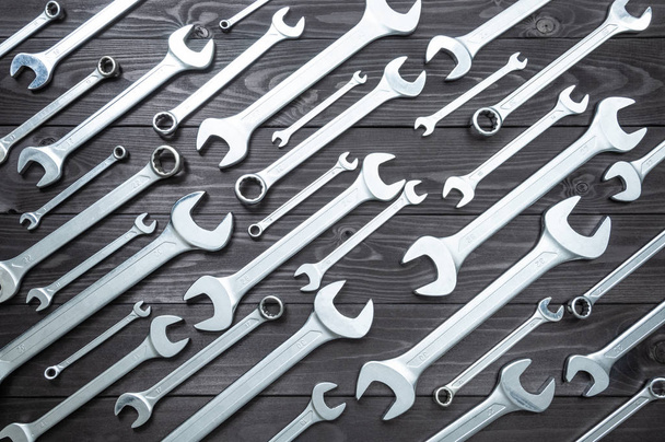 set of chromed wrenches on a dark wooden workbench. top view - Foto, Bild