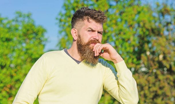 Thoughts concept. Bearded man have rest on sunny day outdoors. Man with beard and mustache on thoughtful face at balcony, trees on background, defocused. Man with long beard enjoy view from balcony - Фото, зображення