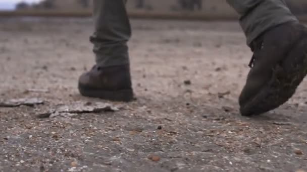 Pernas de homem em moutaineer sapatos pesados andando pela lama no deserto nublado
 - Filmagem, Vídeo