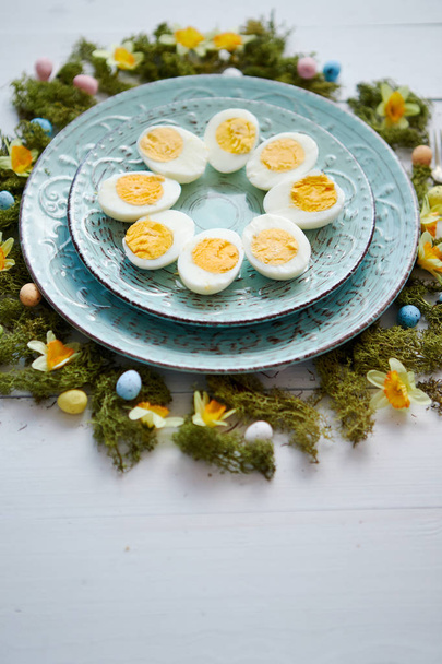 Table de Pâques avec fleurs et œufs. Assiettes décoratives aux œufs durs
 - Photo, image