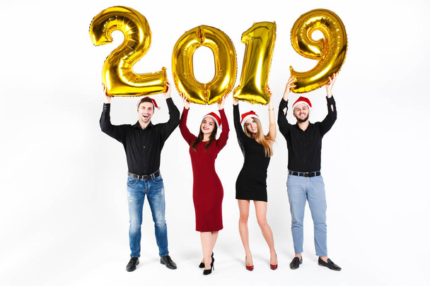 Portrait of group of friends celebrating New Year, standing with balloons with golden numbers in 2019 isolated on white background - Foto, immagini