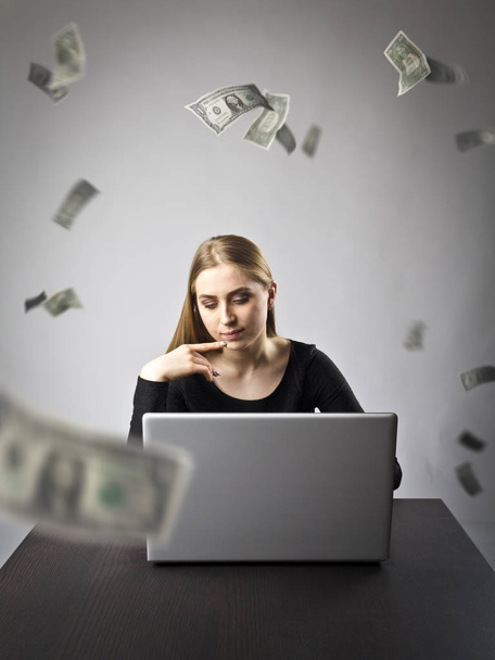 Young woman with laptop. Young woman and falling dollar banknote - Fotó, kép