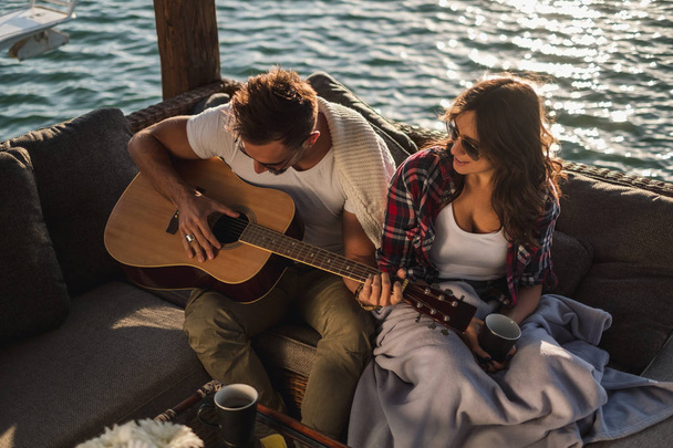 川でギターを弾いて彼女の彼氏を見てのガール フレンド - 写真・画像