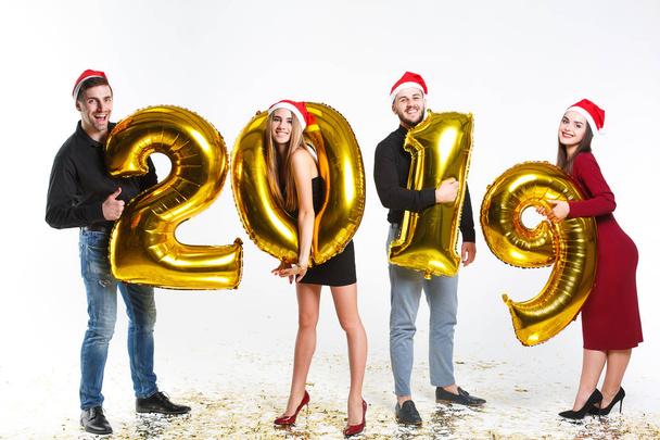 Portrait of group of friends celebrating New Year, standing with balloons with golden numbers in 2019 isolated on white background - Foto, Imagen