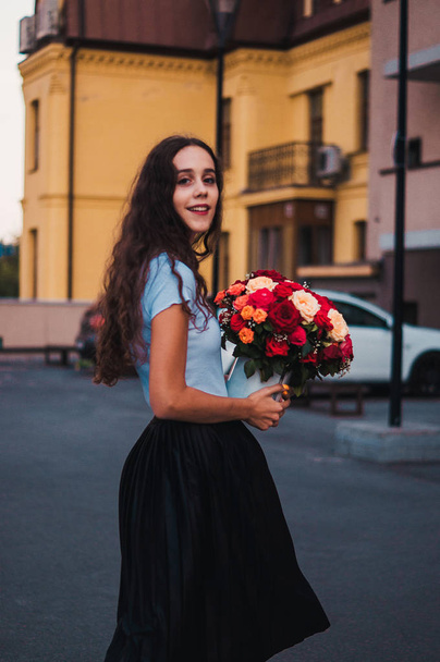 Ευτυχής όμορφη κοπέλα κρατώντας παρόν του μπουκέτο με τριαντάφυλλα  - Φωτογραφία, εικόνα
