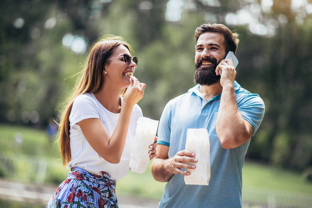 美しい晴れた日にポップコーンを食べて公園で若いカップル - 写真・画像
