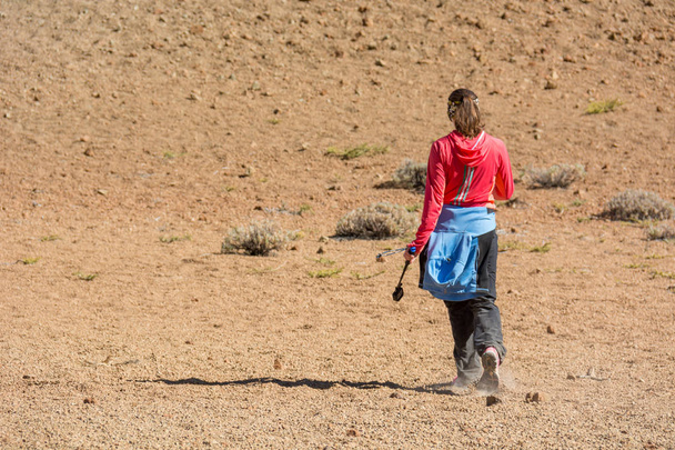 Sporty female hiking desert wasteland across volcanic crater. - Photo, Image