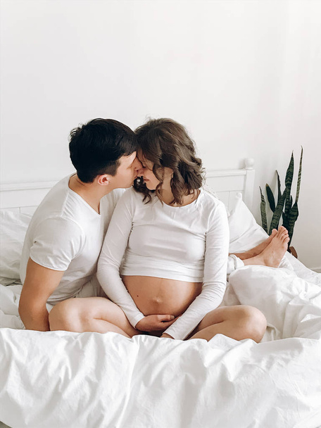 Szczęśliwy mąż młoda całuje żonę w ciąży uśmiechający się i huggin - Zdjęcie, obraz