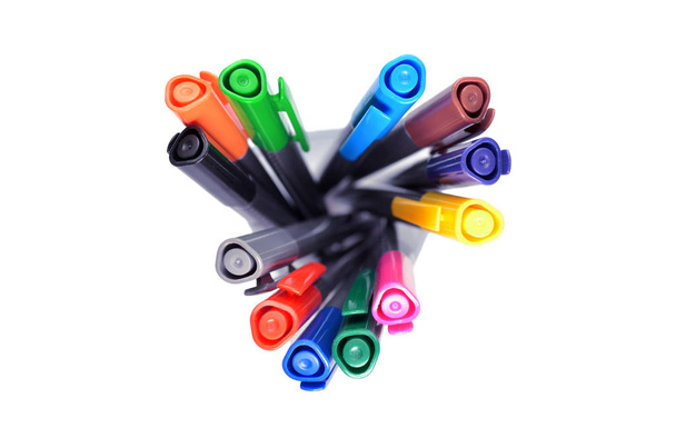 Набір різнокольорових ручок, що стоять у прозорому склі, вид зверху на білому тлі, ізольовані, жахливо орієнтовані
 - Фото, зображення