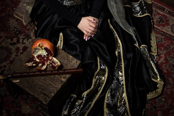 Young woman in armenian national dress sitting with pomegranate and duduk - Zdjęcie, obraz