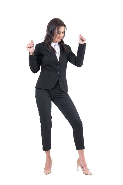 Relaxed cheerful business woman dancing with arms up while looking down. Full body isolated on white background.  - Foto, Imagem