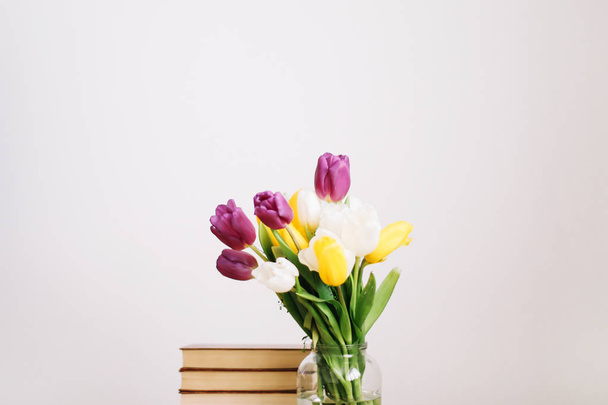 Bouquet of beautiful tulips. Mix of spring tulips flowers. Fresh spring flowers and books on white background.  - Foto, Imagem
